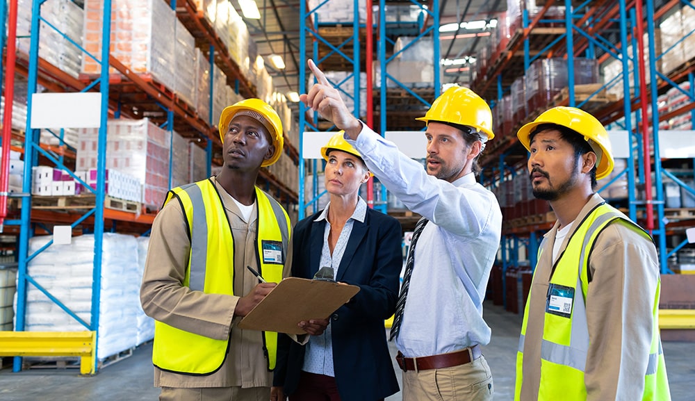 Male supervisor standing with coworkers and pointing at distance