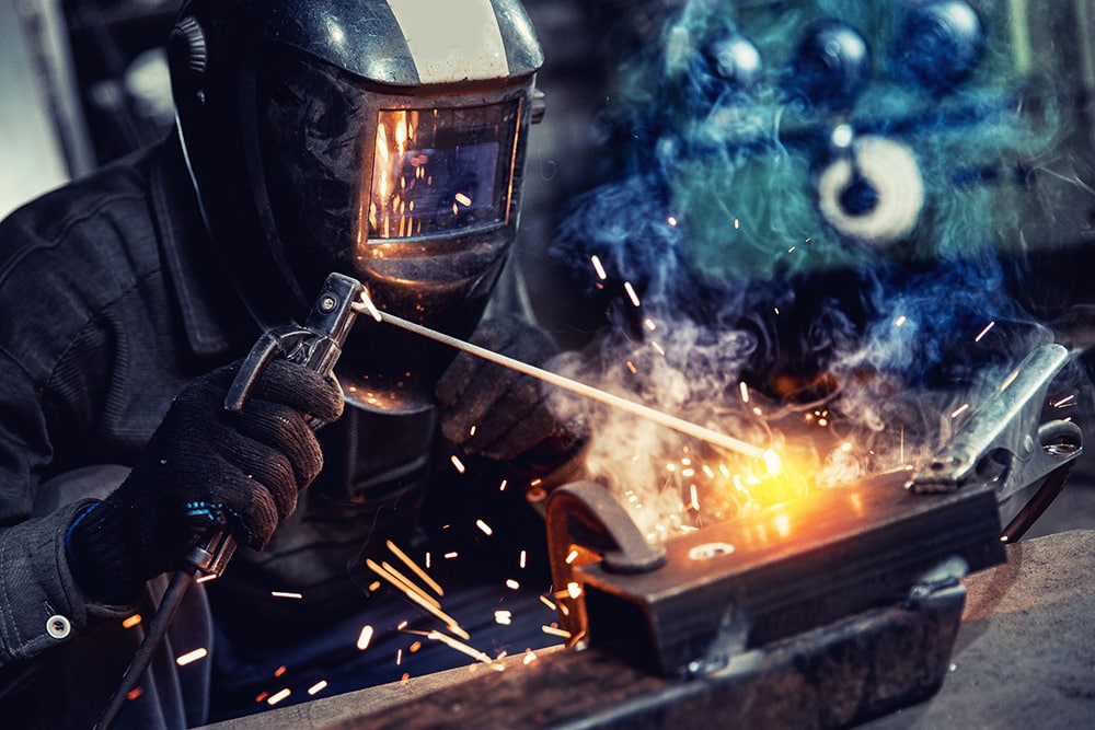 Closeup Industrial welder at factory use equipment mask and tool weld for metalwork with smoke, fire , spark iron.